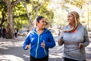Two plus size women jogging in Central Park, New York during a beautiful day.